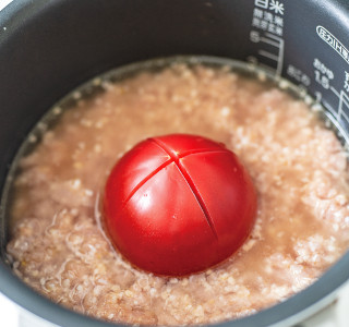 炊飯器に米を入れて2合分の水加減をしたところからトマトの水分量としての60mlを取り除きます。塩を入れて軽く混ぜ、1の鶏肉を入れ、その上にトマトを丸ごとのせて通常通りに炊飯します。