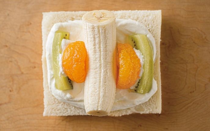 食パンの中心にの1.クリームの1/4をのせ、中央にバナナ、両脇にみかんを置き、クリームを少しはさんでキウイを並べる。その上に同量のクリームをのせ、両端1.5cmをあけて伸ばし、もう1枚の食パンではさむ。