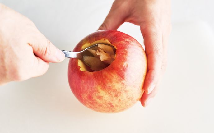 りんごは水でよく洗い、ペティナイフなどで芯と種を取り除き、さらにスプーンを使って下2cm手前までくり抜き、グラニュー糖とバターを詰める。