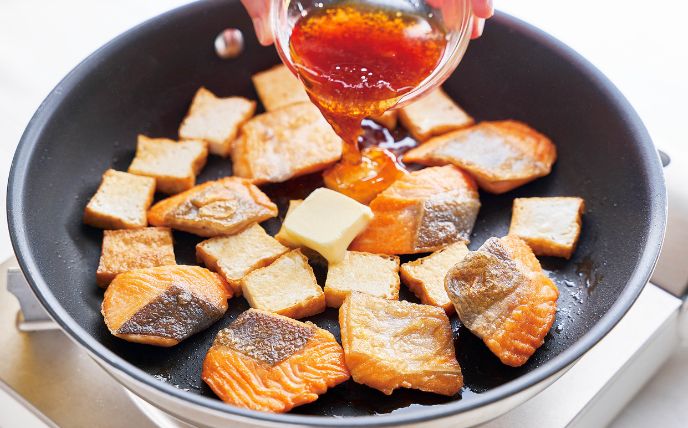 鮭と厚揚げを焼いて調味する<br>
　フライパンに油を入れて中火で熱し、鮭と厚揚げを焼く。2～3分焼いて焼き色が付いたら裏返し、弱火にしてさらに2分ほど焼く。火が通ったらAとバターを加え、さっと絡める。