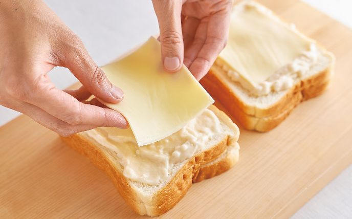 食パンに粒マスタードと食材をのせてサンドし、チーズをのせる<br>
　食パン2枚の片面に粒マスタードを半量ずつ塗り、それぞれにハム2枚、スライスチーズ1枚をのせる。その上に食パンを1枚ずつ重ね、上面にホワイトソース半量と、とろけるスライスチーズを1枚ずつのせる。